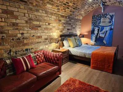 a bedroom with a brick wall with a bed and a couch at The Armoury: Stylish WW1 Bunker in North Queensferry