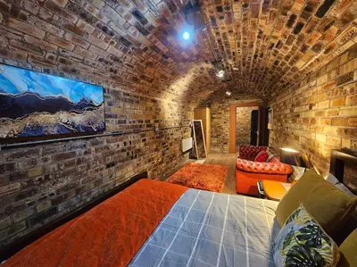 a brick walled room with a bed and a couch at The Armoury: Stylish WW1 Bunker in North Queensferry