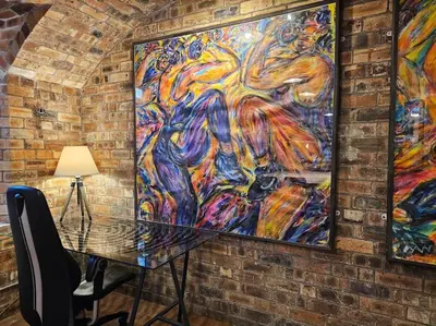 a painting hanging on a brick wall with a table at The Armoury: Stylish WW1 Bunker in North Queensferry