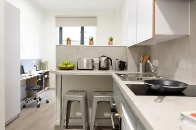 a kitchen with white cabinets and a counter with stools at For Students Only St Mungo's in Glasgow in Glasgow