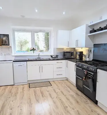a kitchen with white cabinets and a stove top oven at Erradale in Campbeltown