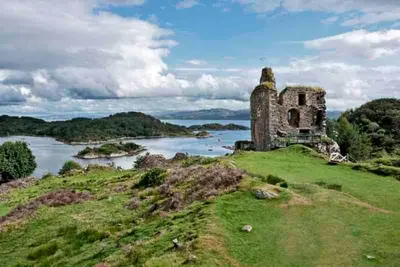 an old building on a hill next to a river at Penlea ~ 1 bedroom Flat with Harbour view in Tarbert