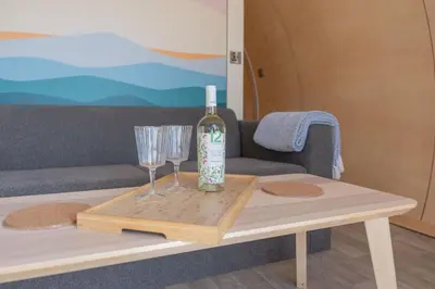 a bottle of wine and two glasses on a coffee table at Port Nan Gael Pods in Pennyghael