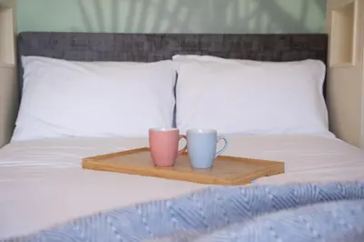 two coffee cups on a wooden tray on a bed at Port Nan Gael Pods in Pennyghael