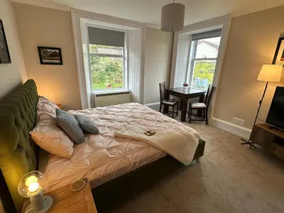 a bedroom with a bed and a table and windows at Room 1, Loch Etive House, Connel near Oban in Connel
