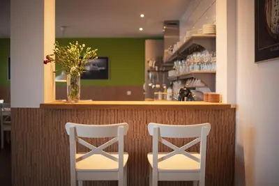 two white chairs sitting at a bar in a restaurant at The Saddlers House - best price per bed in Bowmore