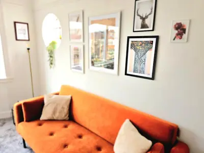 an orange couch in a living room with pictures on the wall at Charming 3-Bed Oasis-free parking in Glasgow