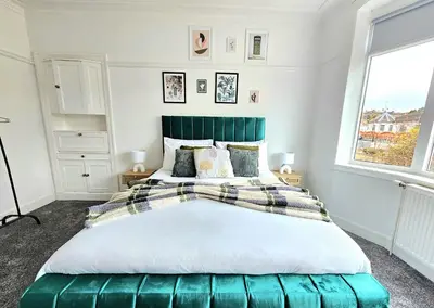 a bedroom with a large bed with a green headboard at Charming 3-Bed Oasis-free parking in Glasgow