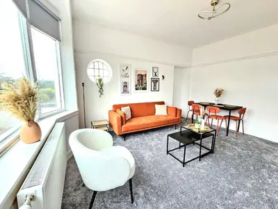 a living room with an orange couch and a table at Charming 3-Bed Oasis-free parking in Glasgow