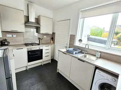 a kitchen with white cabinets and a sink and a window at Charming 3-Bed Oasis-free parking in Glasgow