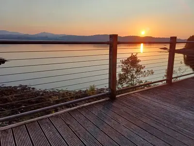 a fence on a boardwalk with the sunset in the background at Tigh na Breac - Great Outdoor Activity Location Oban in Bonawe