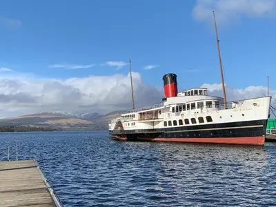 a large boat is docked in the water at Ptarmigan Lodge in Balmaha