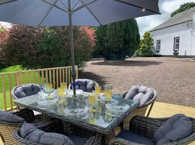 a table with glasses and an umbrella on a patio at WestLaigh Lrg Luxury Country Farm House 20 min from the city in Glassford