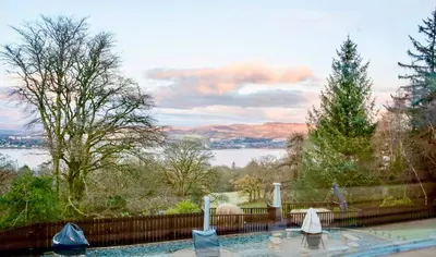 a swimming pool with a view of a lake at Gleddoch Coach House in Langbank