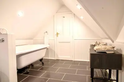 a white bathroom with a tub and a sink at Gleddoch Coach House in Langbank