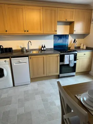 a kitchen with wooden cabinets and a sink and a dishwasher at Island View - Spacious Two Bedroom Oban Apartment with Sea Views in Oban