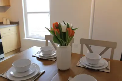 a vase of tulips sitting on top of a wooden table at Island View - Spacious Two Bedroom Oban Apartment with Sea Views in Oban