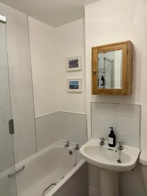 a bathroom with a sink and a tub and a mirror at Island View - Spacious Two Bedroom Oban Apartment with Sea Views in Oban