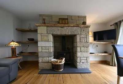 a living room with a stone fireplace with a basket at Avoca Lodge in Fort William