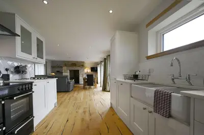 a kitchen with white cabinets and a wooden floor at Avoca Lodge in Fort William