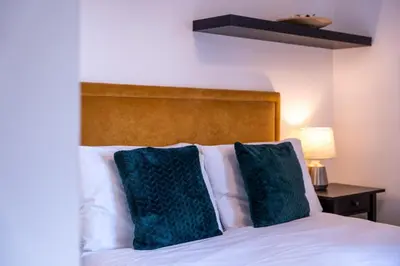 a bed with two green pillows on top of it at Ardbeg Apartment in Oban