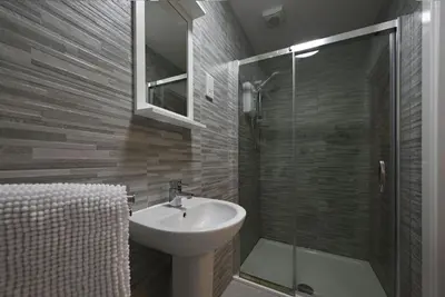 a bathroom with a sink and a glass shower at Ardbeg Apartment in Oban