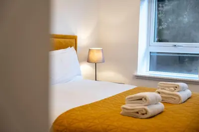 a bedroom with a bed with towels on it at Bowmore Apartment in Oban