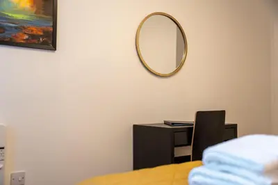 a mirror on a wall above a desk with a chair at Bowmore Apartment in Oban