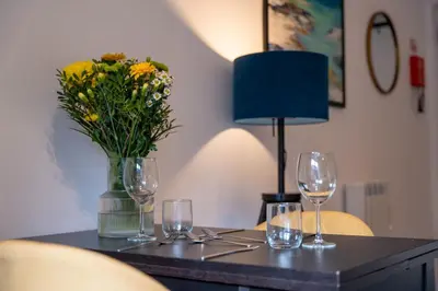 a table with glasses and a vase of flowers on it at Jura Apartment in Oban