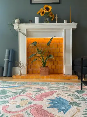 a living room with a brick fireplace with a plant at 1 The Cairn Kilmartin - Beautiful Victorian Flat, Pet Friendly in Kilmartin
