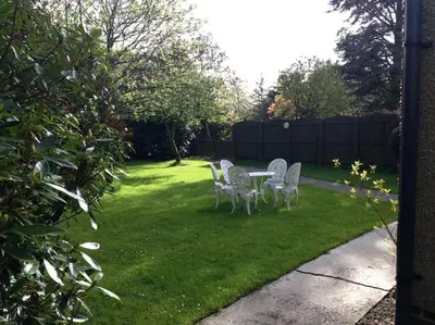 a yard with chairs and a table in the grass at Garden Cottage Helensburgh in Helensburgh