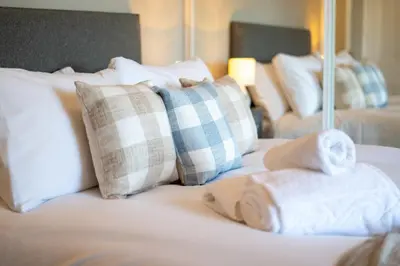 a bed with white pillows and towels on it at South Beach View in Troon