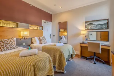 a hotel room with two beds and a desk at Apex Dunblane Hydro in Dunblane