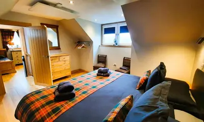 a bedroom with a king sized bed and a couch at Clarinnes Cottage in Luss