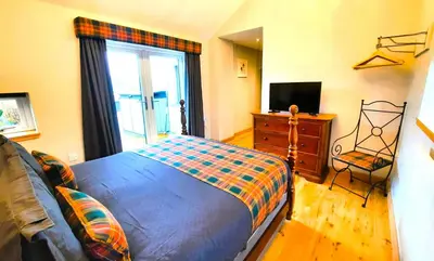 a bedroom with a bed and a tv and a window at Clarinnes Cottage in Luss