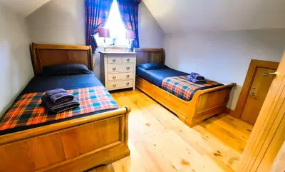 a bedroom with two beds and a dresser at Clarinnes Cottage in Luss
