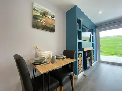 a dining room with a table and chairs and a window at Laigh Letterpin Lodge in Girvan