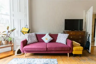 a living room with a purple couch and a tv at Palm Tree Apartment- Period Home with Cat in Edinburgh