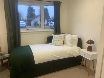 a bed in a room with a window at Sleeps7-Parking-Garden-Patio in Johnstone