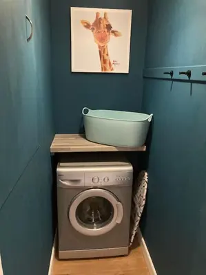 a laundry room with a washing machine and a painting on the wall at Rustic Top Floor West End Pad With Balcony, Parking next to Byers Road, Aston Lane, Glasgow Uni in Glasgow
