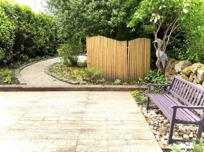 a purple bench in a garden with a fence at Keppochhill - Beautiful Home with Hot Tub in Banton