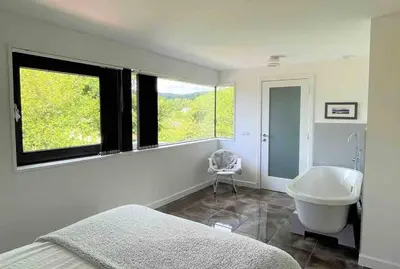a bedroom with a tub and a sink and a window at Keppochhill - Beautiful Home with Hot Tub in Banton