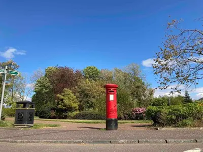 a red post box sitting in the middle of a road at Keppochhill - Beautiful Home with Hot Tub in Banton