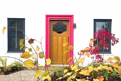 a yellow door with a red frame on a white house at Keppochhill - Beautiful Home with Hot Tub in Banton