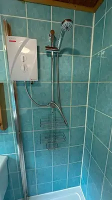 a shower in a bathroom with blue tiles at 1 Bedroom Cabin with Mountain & Loch Views - Quiet Location between Glencoe & Ben Nevis in Corran