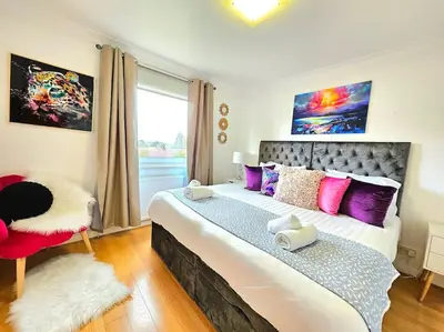 a bedroom with a large bed with purple pillows and a window at 3 Bed House with 6 Beds by Sensational Stay in Edinburgh