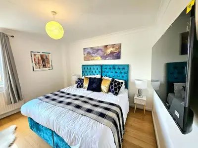 a bedroom with a large bed with a blue headboard at 3 Bed House with 6 Beds by Sensational Stay in Edinburgh
