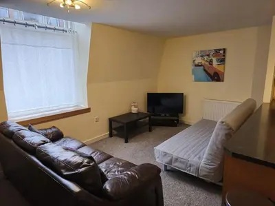 a living room with a leather couch and a television at 2 Bedroom Modern stylish Apt in Glasgow City Centre in Glasgow