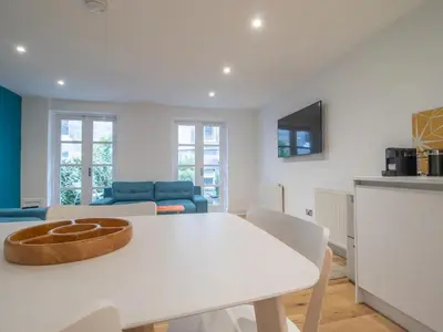 a kitchen and living room with a white table and chairs at Stylish West End Detached Mews - Pass the Keys in Glasgow