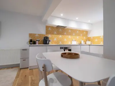 a white kitchen with a white table and chairs at Stylish West End Detached Mews - Pass the Keys in Glasgow